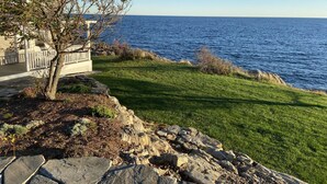 A coastal property with a grassy lawn, a stone retaining wall, and a view of the ocean. - Ocean Front at Fortunes Rocks (Fortunes Rocks)