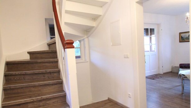 A staircase with wooden steps and a red handrail leading to an upper floor. - Alpenschloss (Garmisch-Partenkirchen)