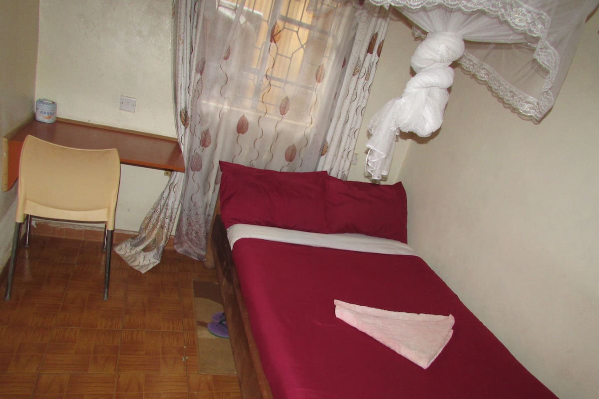 Un dormitorio pequeño y ordenado con una cama individual, una silla y un escritorio.