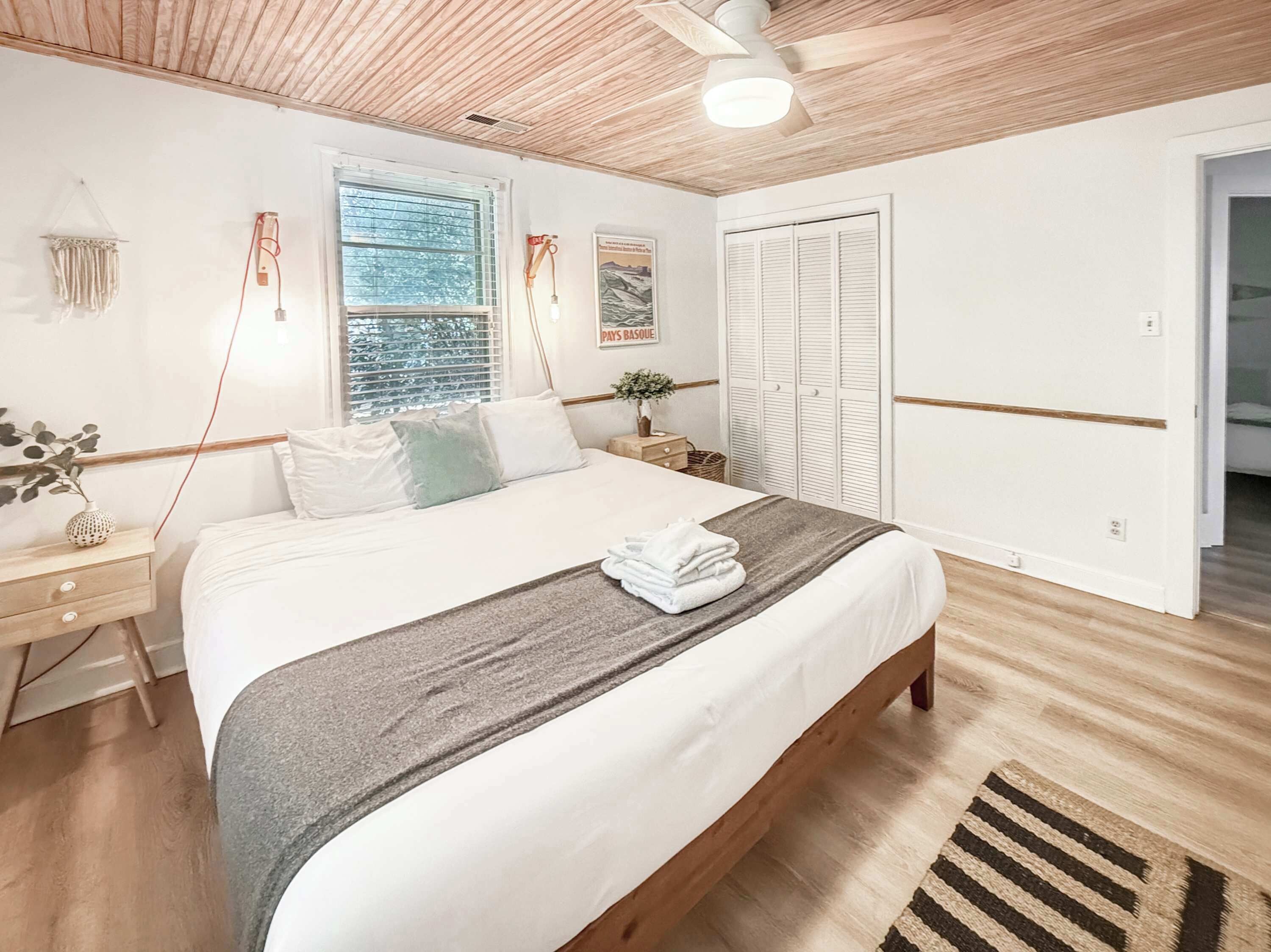A bedroom with a bed, bedside tables, a window, a wardrobe, and a ceiling fan.