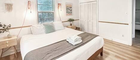 A bedroom with a bed, bedside tables, a window, a wardrobe, and a ceiling fan.