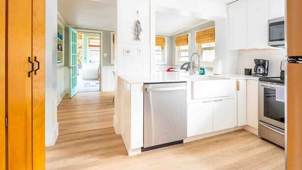 A modern kitchen with white cabinetry, a dishwasher, a stove, and a microwave.