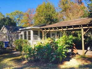 Ein Haus mit einer Veranda, einer Garage und einem Garten mit verschiedenen Pflanzen.
