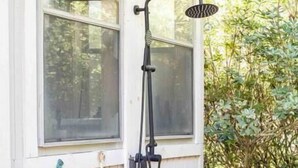 A window with a showerhead and hose, a small shelf, and a window handle.