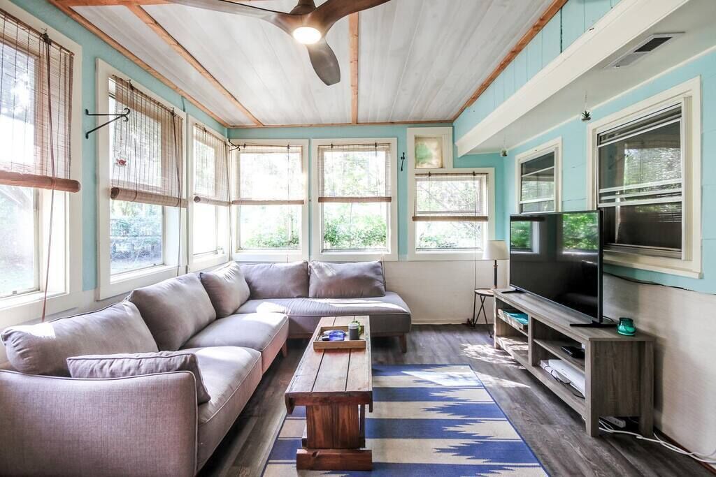 A living room with a sofa, a coffee table, a TV, and a ceiling fan.