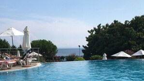 A swimming pool with lounge chairs and umbrellas, a wooden deck, and a view of the sea. - 3 Bed Apt, Garden of Eden, St Vlas, Bulgaria (Sveti Vlas)