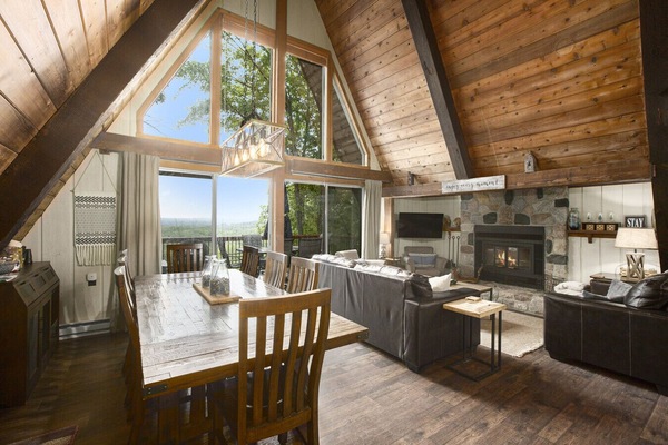 Vaulted living room w/ wall of windows, stone fireplace, and incredible natural light