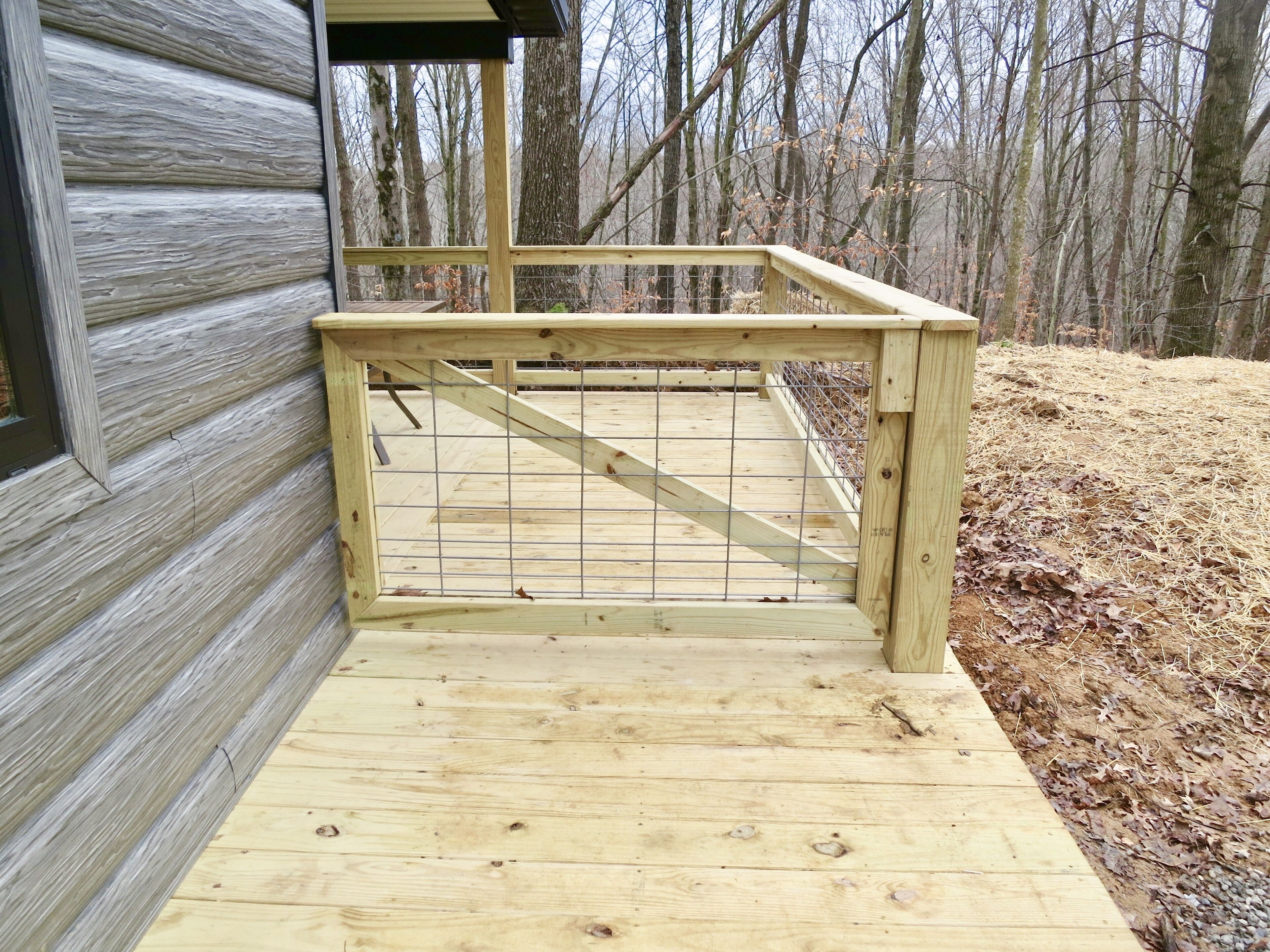 A wooden deck with a metal gate leading to a building.