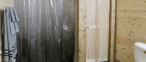 Un baño de madera con cortina de ducha, un inodoro y un perchero para toallas.