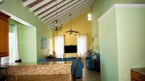 Amplia sala de estar con cocina, comedor y zona de estar con sofás azules.