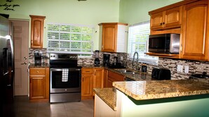 Una cocina moderna con armarios de madera, electrodomésticos de acero inoxidable y encimera de granito.