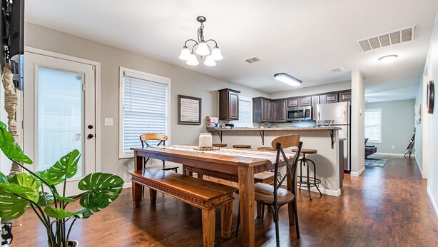A spacious kitchen with wooden cabinets, a central island, and a dining area with a wooden table and benches.