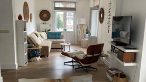 A modern living room with a large leather rug, a sofa, a coffee table, and a TV. - Charming renovated luxury apartment with seaview. (De Haan)