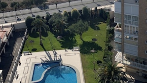 Edifici residencial amb piscina, vistes al mar i carretera amb palmeres.