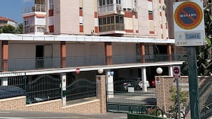 Un edifici d'apartaments de diversos pisos amb balcons, una entrada tancada i un senyal que indica prohibit aparcar.