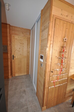Una puerta de madera con decoración de estrella y un lazo rojo, suelo de baldosas y una lámpara en el techo.