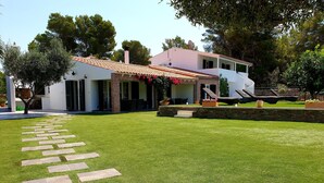 Una casa moderna con un césped bien cuidado, un sendero de piedra y mobiliario exterior.