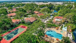 An aerial view of a residential area with houses, a tennis court, a swimming pool, and a lake. - Sandy Shores Villa near Sieta Key and other beaches (Sarasota)