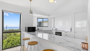 A modern kitchen with a large island, white cabinetry, and a view of the ocean. - Castaway Cove Castaways Beach (Castaways Beach)