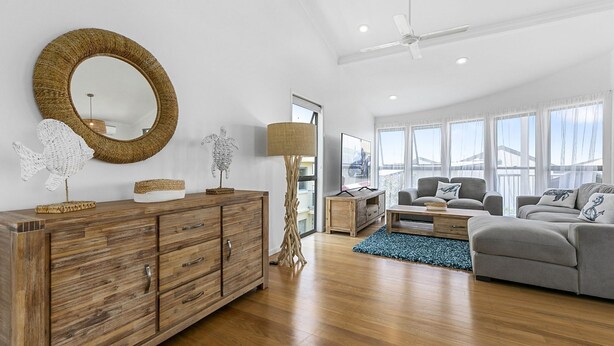 A spacious living room with a wooden cabinet, a round mirror, and a modern sofa. - Castaway Cove Castaways Beach (Castaways Beach)