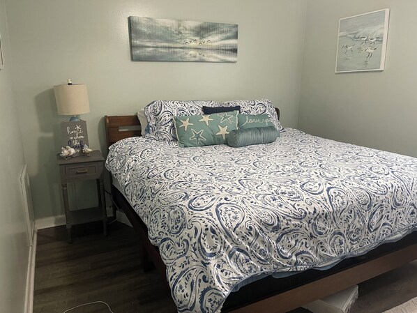 Un dormitorio con cama, mesita de noche, lámpara y decoración en la pared.