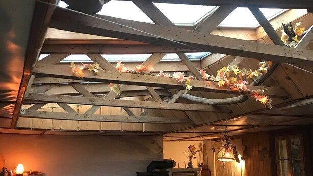 Ein gemütliches Zimmer mit Holzbalkendecke, Kamin und Sofa.