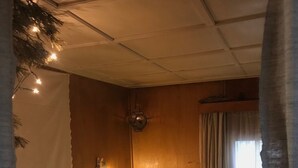 Ein gemütliches Schlafzimmer mit einem hölzernen Kopfteil, einer Nachttischlampe und einem Fenster mit Vorhängen.