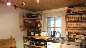Eine gemütliche Küche mit Holzschr änken, einem Esstisch mit Kerze und einem Fenster mit Vorhängen.