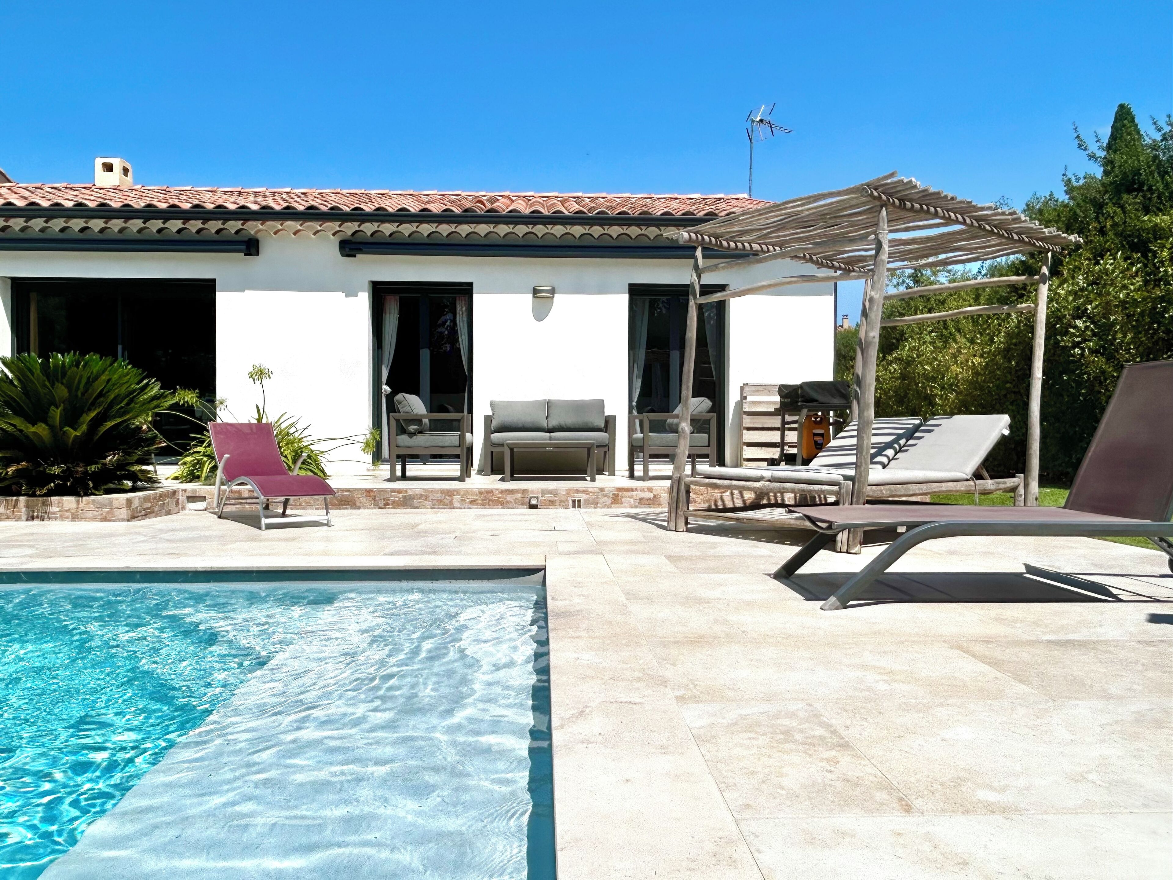 Ein Poolbereich mit klarem Pool, Liegestühlen und einer Pergola.