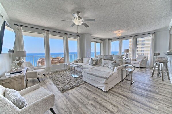 A spacious bedroom with a large bed, a ceiling fan, and a view of the ocean.