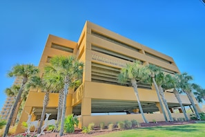 A modern hotel with a flat facade, palm trees, and a sign indicating it's a condominiums.
