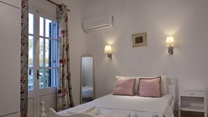 Ein Schlafzimmer mit Bett, Nachttischlampen, einem Nachttisch, einem Kleiderschrank und einer Klimaanlage.