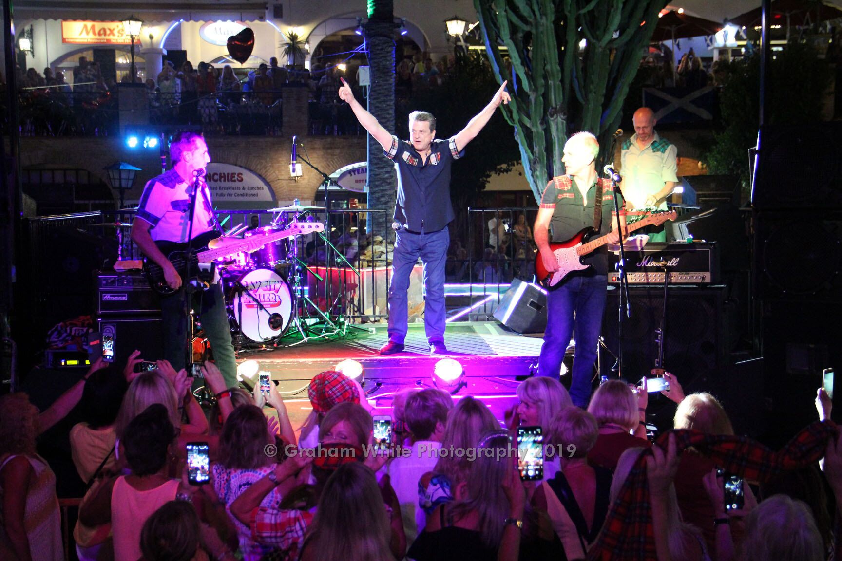 A band performing on a stage with a crowd in the foreground.