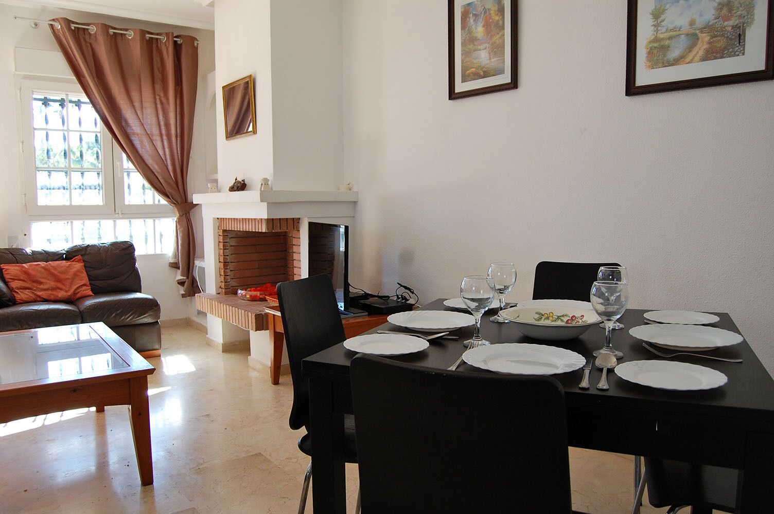 A dining area with a brick fireplace, a sofa, and a TV.
