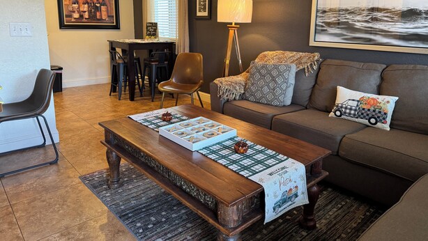 Un salon comprenant un canapé, une table basse, une lampe, un fauteuil et un coin repas avec une table et des chaises.