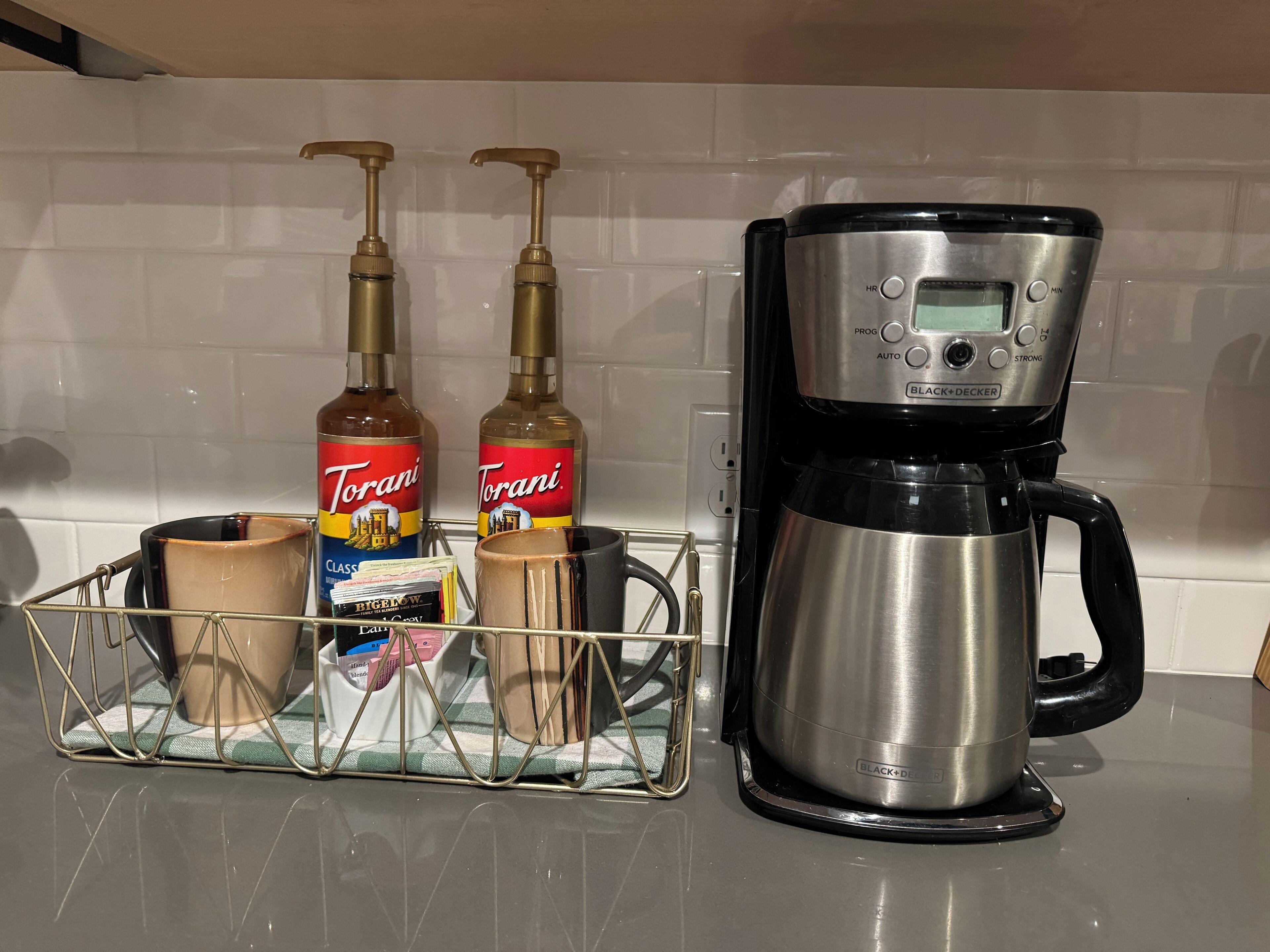 A kitchen counter with a coffee maker and two Torani syrup bottles.