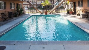 Une piscine rectangulaire à l’eau d’un bleu limpide, entourée de chaises longues et de plantes en pot.