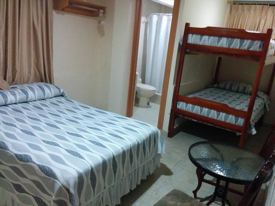 Una habitación con una cama litera, una cama individual, una silla y un inodoro.