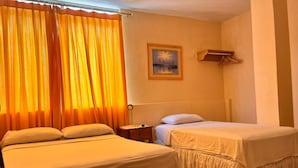 Habitación de hotel con dos camas, una mesita de noche, un cuadro en la pared y una ventana con cortinas.