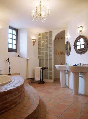 Un baño con bañera independiente, ventana, zona de ducha y lavabo.
