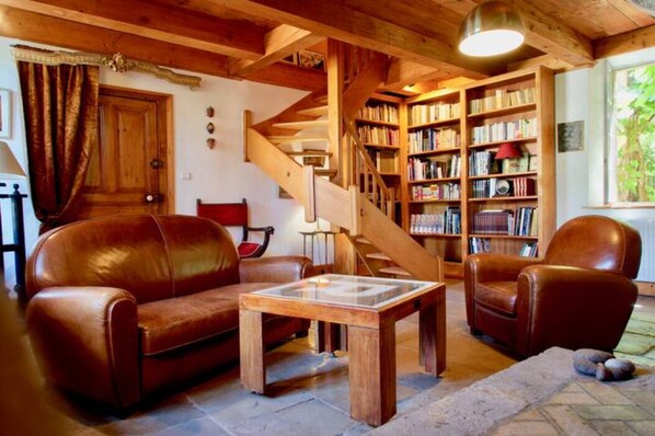 Una sala de estar acogedora con sofás de cuero, una mesa de centro de madera y una estantería.