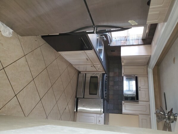 Modern kitchen with white cabinetry, dark countertops, and stainless steel appliances.