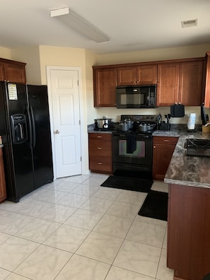 Enjoy cooking in this well-lit kitchen with a refrigerator, stove, and microwave.