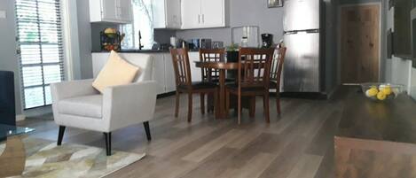 A modern kitchen with white cabinets, a dining table with chairs, and a refrigerator.
