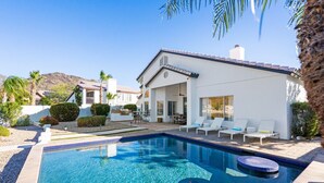 Ein modernes Haus mit Pool, Sitzgelegenheiten im Freien und Bergblick.