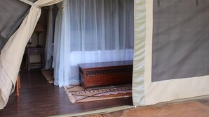 Una carpa con una cama, una mesita de noche y una alfombra estampada en su interior.