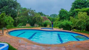 Una piscina con cubierta de piedra, rodeada de exuberante vegetación y árboles.