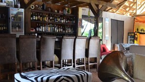 Un rincón de bar acogedor con muebles de madera, un otoman con estampado de cebra, un tocadiscos antiguo y una estantería de bar bien surtida.