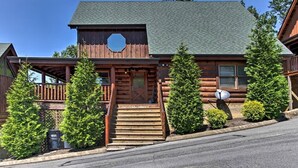 A log cabin with a wooden exterior, a front porch, and a satellite dish.