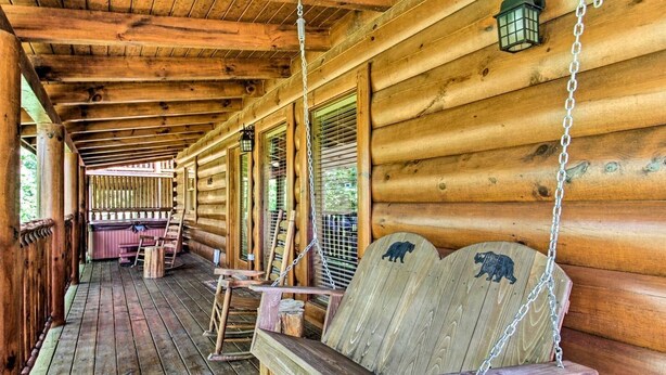 A wooden cabin with a porch, wooden benches, and a swing.